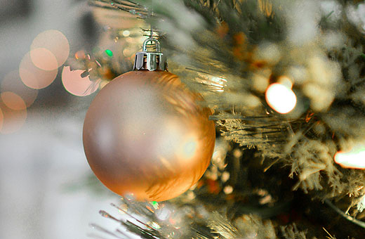 Close up photo of a metallic gold-colored ball hanging from a Christmas tree